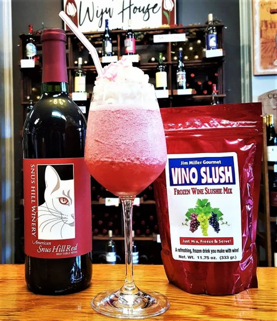 Prepared Vino Slush frozen wine cocktail served in a glass next to a wine bottle and mix pouch, perfect for entertaining, summer gatherings, and refreshing drinks.