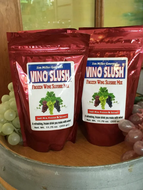 Two pouches of Vino Slush wine slushie mix displayed with fresh grapes, showcasing premium frozen cocktail mix for homemade wine slushies and party beverages.