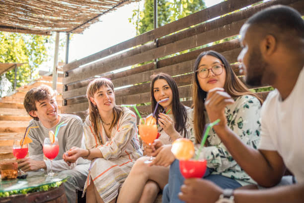Friends enjoying colorful frozen drinks together at an outdoor party.